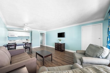 A hotel room with a bed, a sofa, a desk, and a painting on the wall. at Boardwalk Beach Hotel