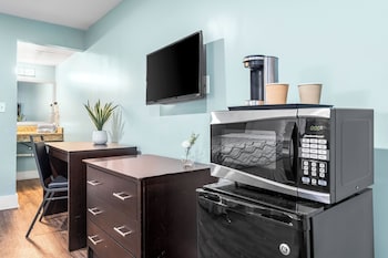 A kitchen with white cabinets, a stainless steel refrigerator, a microwave, a sink, and a stove. at Boardwalk Beach Hotel