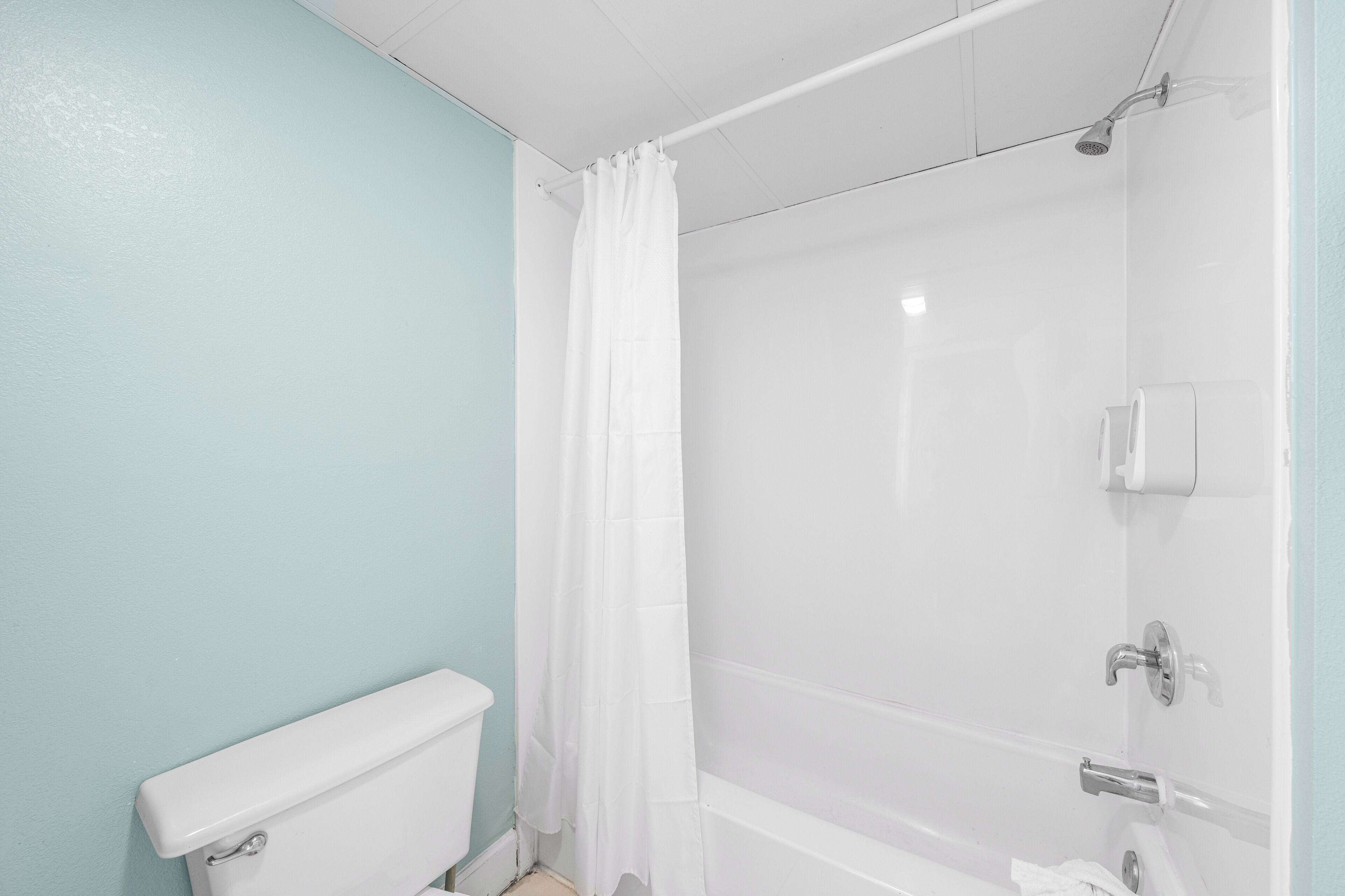 Ein Badezimmer mit Toilette, einer Duschkabine mit Glastür und einem weißen Vorhang.