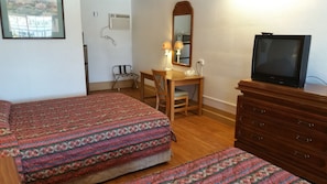 A hotel room with two beds, a desk with a chair, a television, and a dresser. - Tri-State Inn (Kingman)