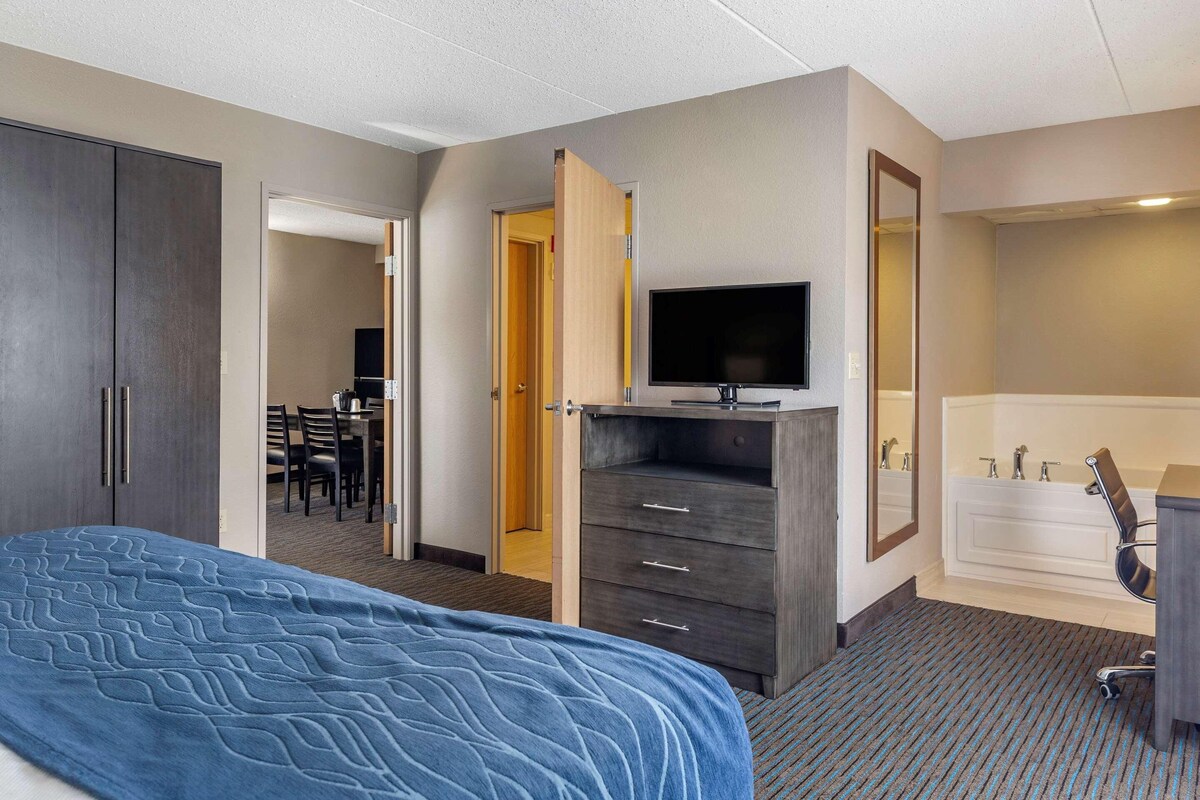 Una habitación de hotel con cama, televisor, escritorio y baño.
