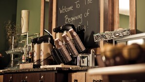 Una estación de café con un pizarrón que dice “¡Bienvenido al comienzo del día!” y diferentes equipos para preparar café.