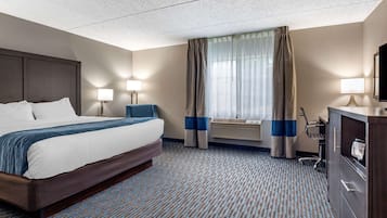 Una habitación de hotel con una cama grande, dos lámparas de noche, un escritorio con silla y un televisor.