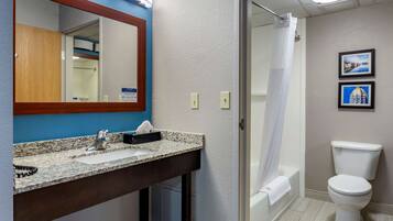 Un baño con lavamanos de encimera de granito, un espejo, inodoro y cortina de ducha.