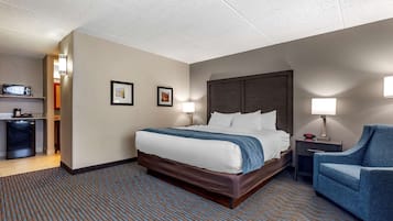 Ein Hotelzimmer mit einem Bett, einem Schreibtisch, einem Stuhl, einer Mikrowelle und einem kleinen Kühlschrank.