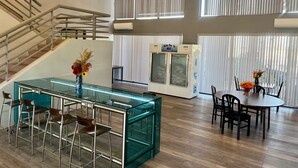 A spacious indoor area with a staircase, a bar area with stools, a dining table with chairs, and a vending machine. - Studio 6 Suites Lake Havasu City, AZ  (Lake Havasu City)