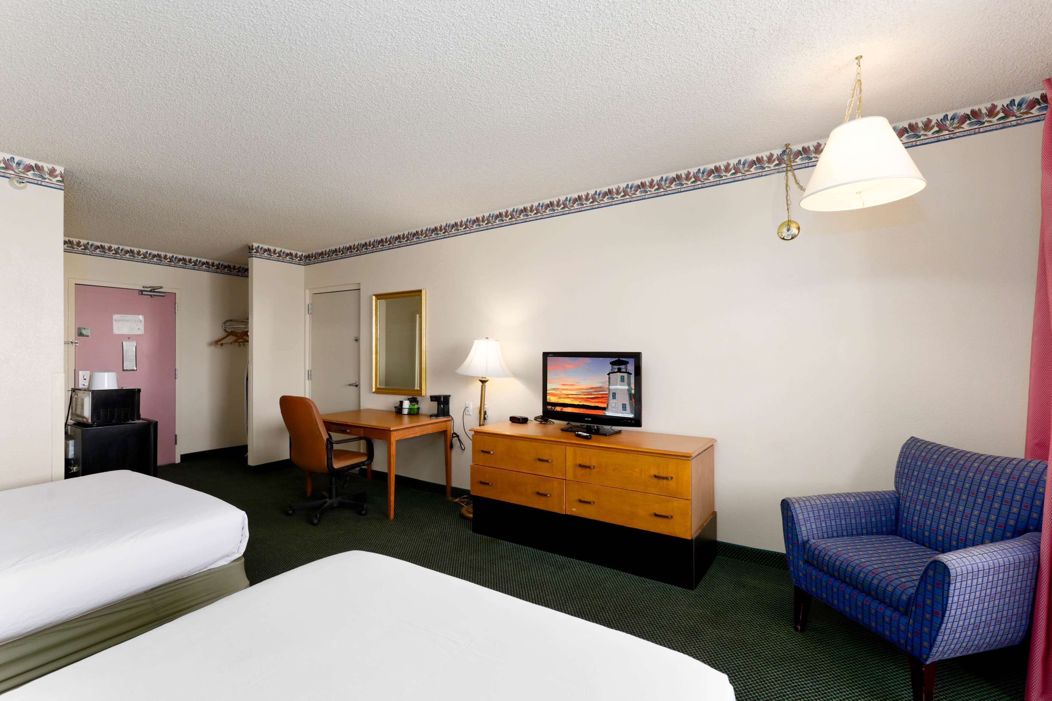 A hotel room with two beds, a desk with a computer, a television, a chair, and a dresser.