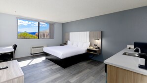 A modern hotel room with a large bed, a desk, a kitchenette, and a view of the outdoors. - Studio 6 Suites Lake Havasu City, AZ  (Lake Havasu City)