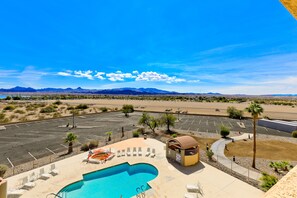 Zona de piscina con sillones, una piscina pequeña y vistas a montañas al fondo.