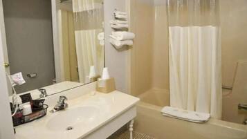 Un baño con lavamanos, espejo y cabina de ducha con cortina.