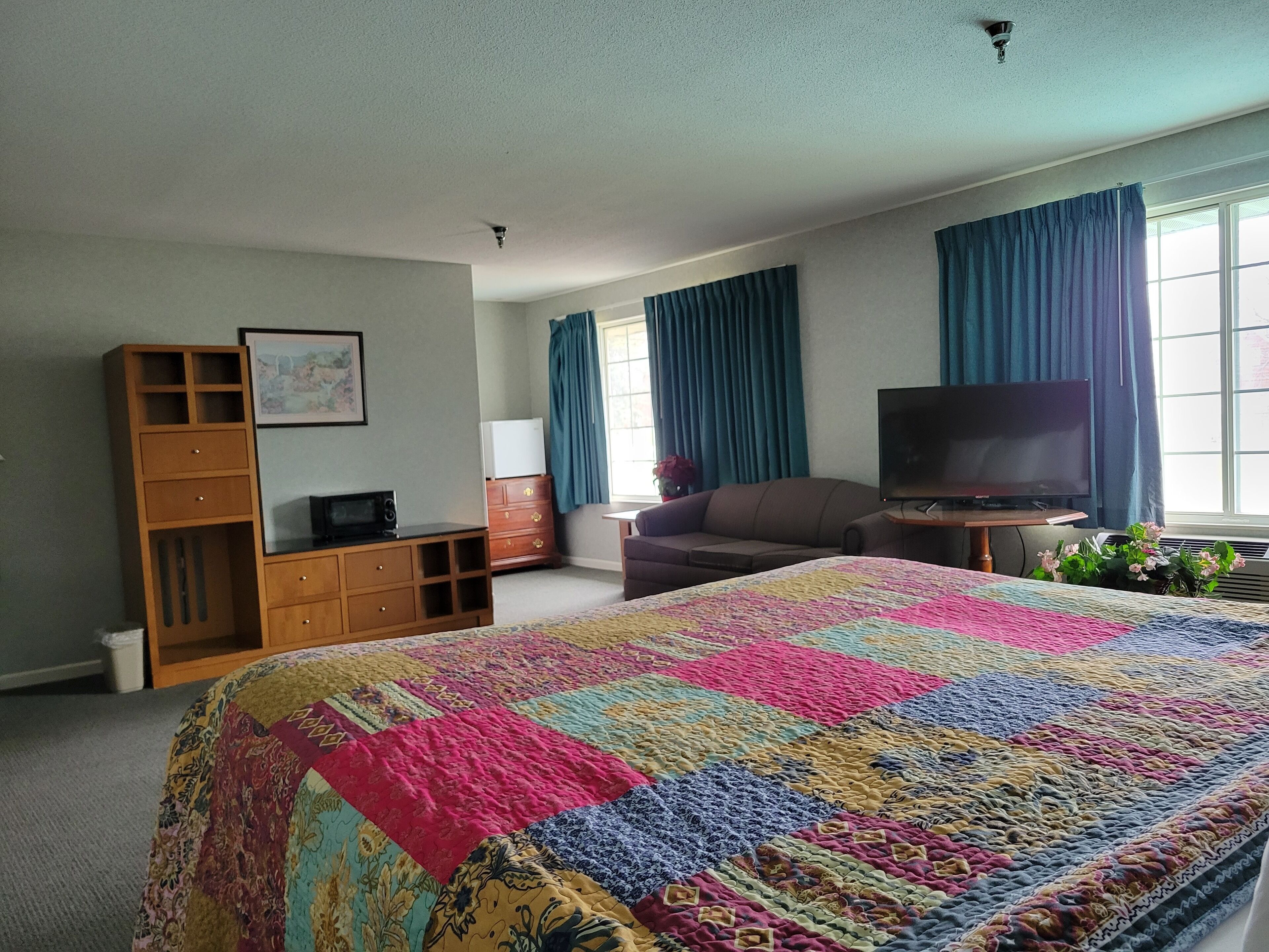 A bedroom with a large bed, a television, a sofa, and a dresser.