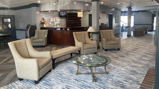 A lobby with a reception desk, seating area, and a patterned carpet.
