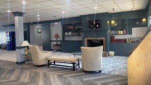 A spacious lobby with a fireplace, bookshelves, a television, and comfortable seating.