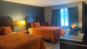 A hotel room with two beds, a desk, a chair, a TV, and a window with curtains.