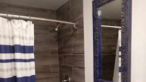 A bathroom with a shower, a sink, and a mirror.