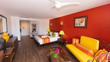 A hotel room with a bed, a sofa, a desk, and a ceiling fan.