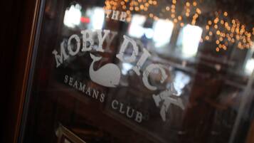 A window with the text "THE MOBY DICK SEAMANS CLUB" and a reflection of lights.