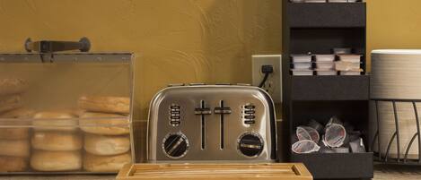 Un comptoir de cuisine avec un grille-pain, un présentoir à pain et une étagère contenant des récipients.