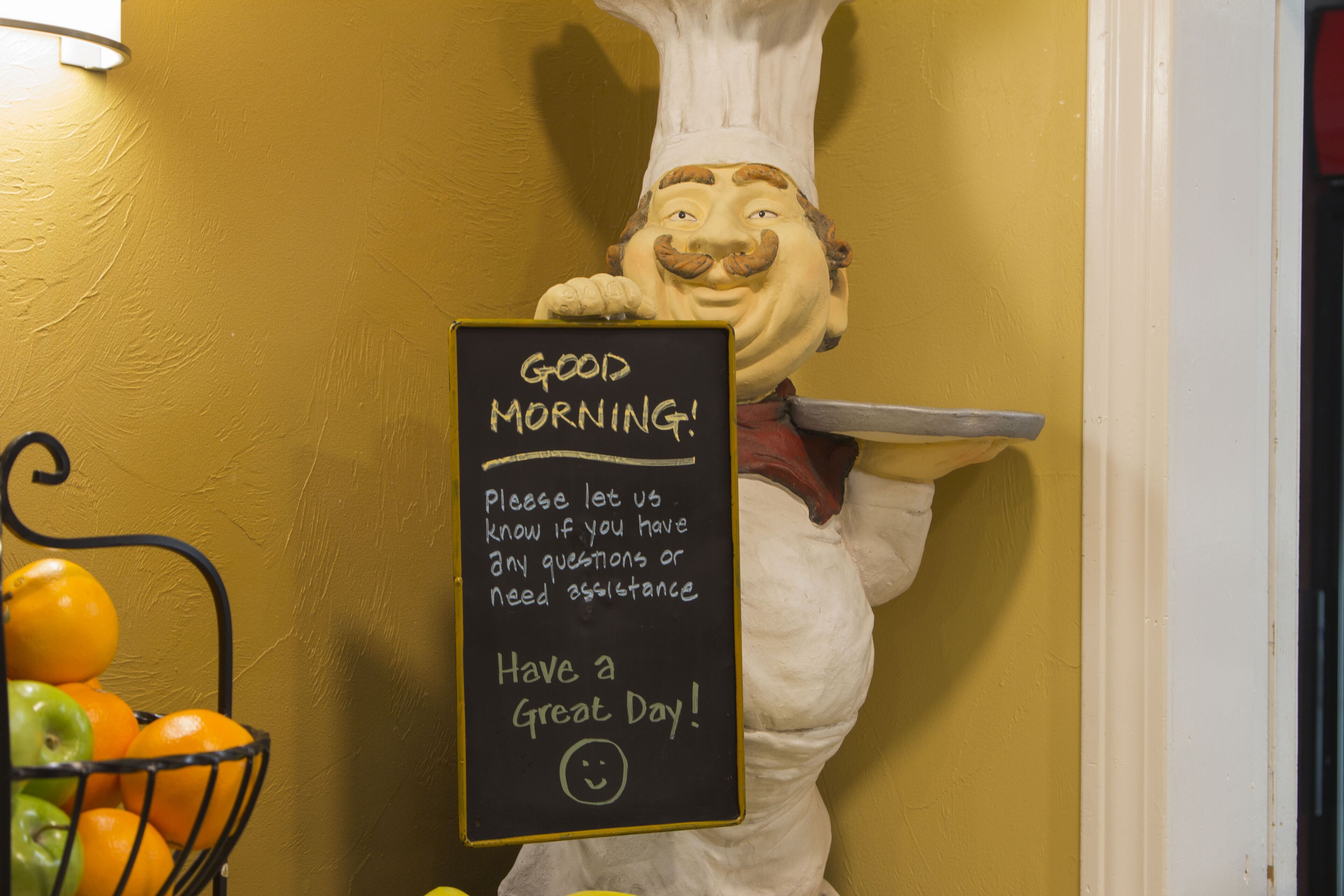 A chef statue holding a tray and a chalkboard with a message.