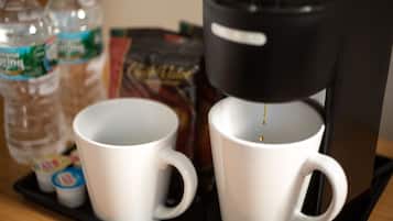 Une machine à café, deux tasses blanches et deux bouteilles d’eau sur un plateau.