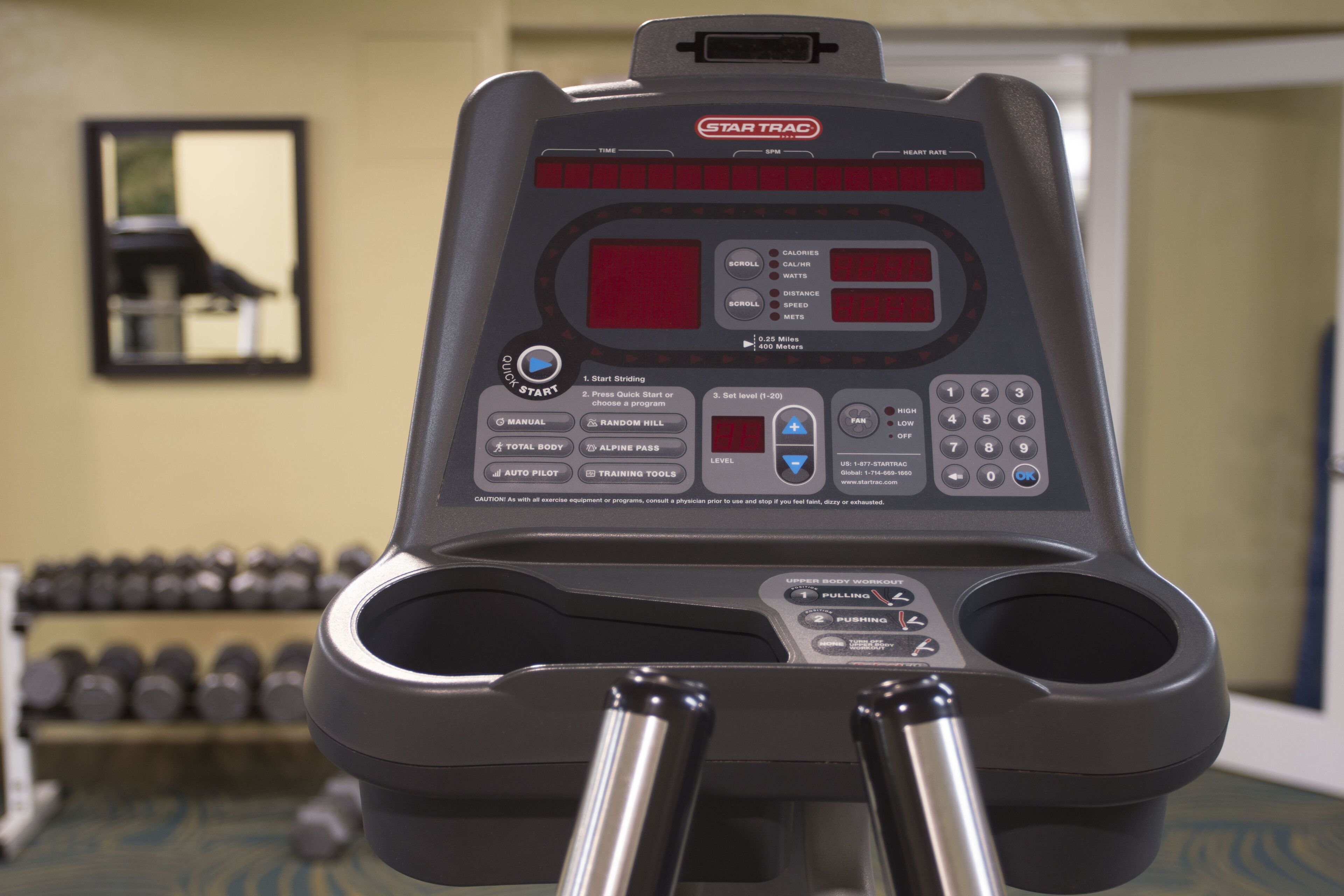 A treadmill with a digital display, control buttons, and a handrail.