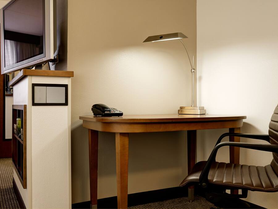Een hoekappartement met een houten bureau, een stoel, een bureaulamp en een telefoon.