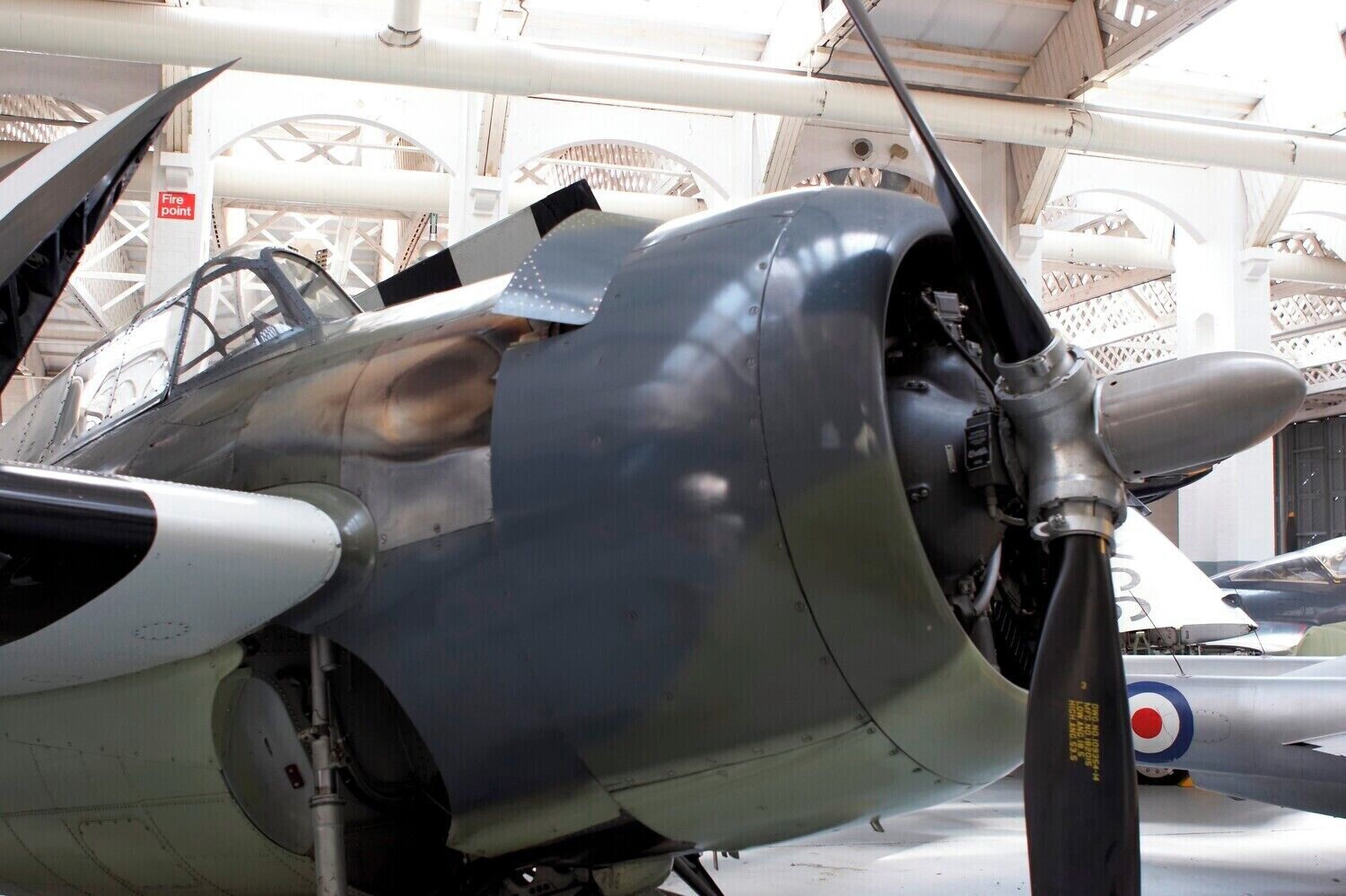 A close-up of an aircraft's nose and engine, with a "Fire point" sign visible in the background.