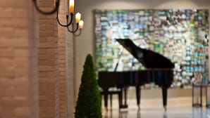 Un grand piano dans un hall spacieux, doté d’un sol carrelé et agrémenté d’une plante en pot.