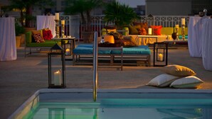 Un espace piscine aménagé sur le toit, avec des chaises longues, des tables et des bougies.