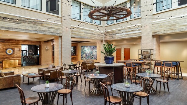 Un hall d’entrée spacieux avec de nombreux espaces de détente, un bar central et un grand lustre.