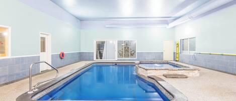 An indoor swimming pool with clear water, a lifeguard chair, and a safety ring.