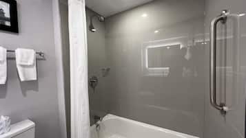 Un baño moderno con ducha envuelta en vidrio, una bañera blanca y un inodoro.