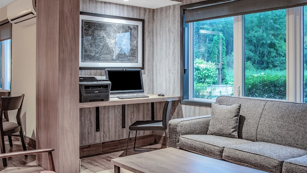 A modern living room with a wooden desk, a computer, and a sofa. - Super 8 by Wyndham Cornwall ON (Cornwall)
