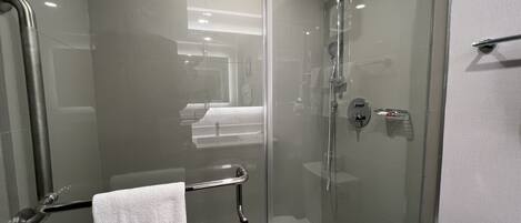 Un baño moderno con ducha envuelta en vidrio, una bañera blanca y una puerta de vidrio.