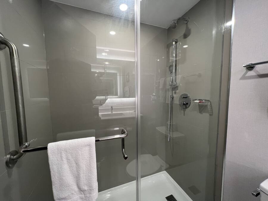 Un bagno moderno con doccia vetrata, una vasca da bagno bianca e un'anta in vetro.