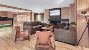 A modern living room with a sofa, chairs, a coffee table, and a TV. - Super 8 by Wyndham Cornwall ON (Cornwall)
