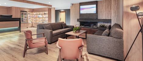 Un salon moderne avec un canapé, des fauteuils, une table basse et un téléviseur.