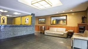 A lobby with a reception desk, a sofa, a coffee table, and a fireplace.