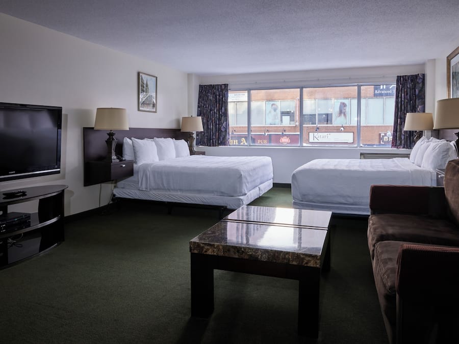 Una habitación de hotel con dos camas, un televisor, una mesita de centro y un sofá.