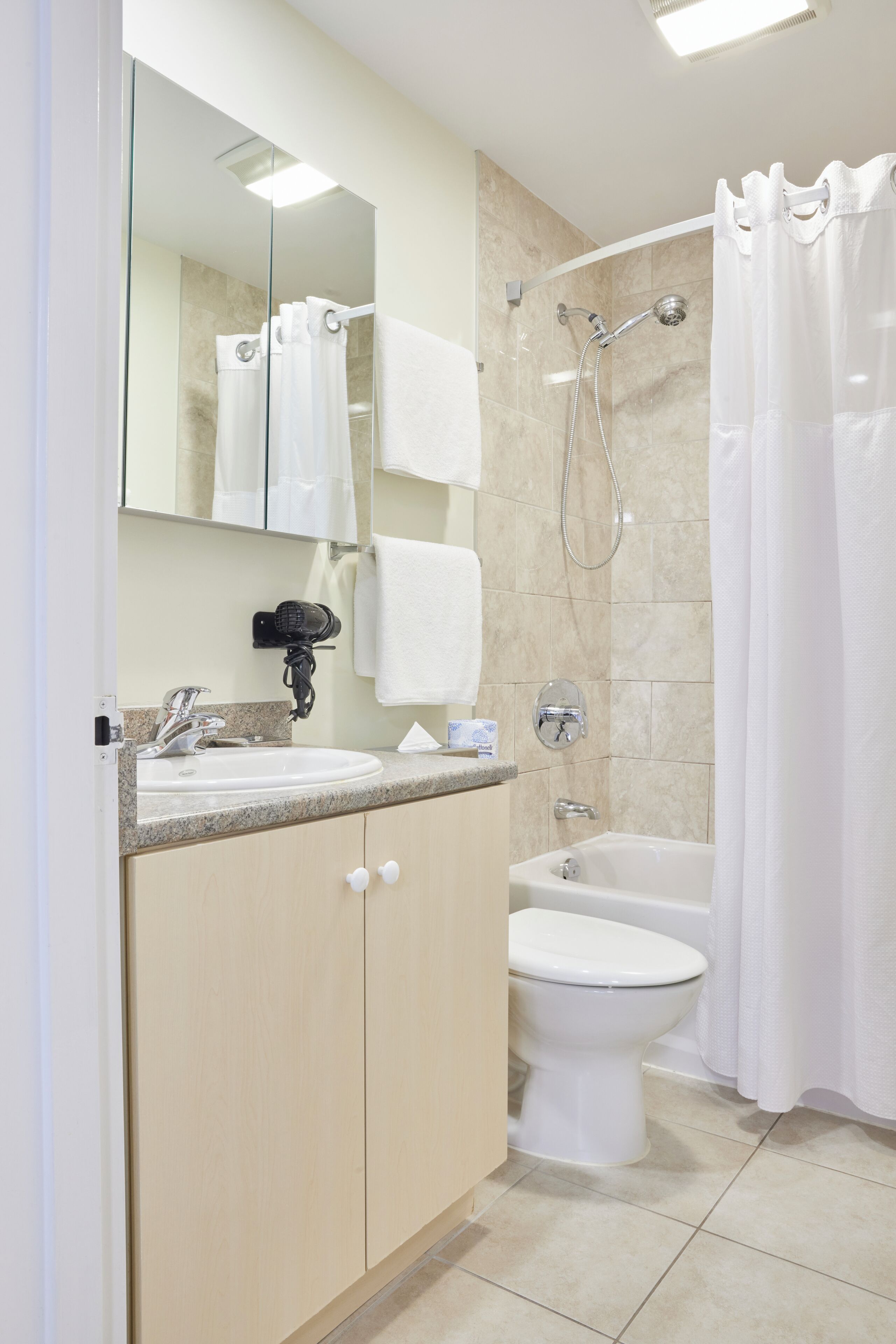 Un bagno moderno con lavandino, specchio, portasci, doccia e WC.