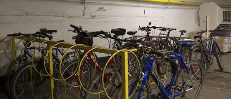 A bike parking area with multiple bicycles secured to a yellow rack.