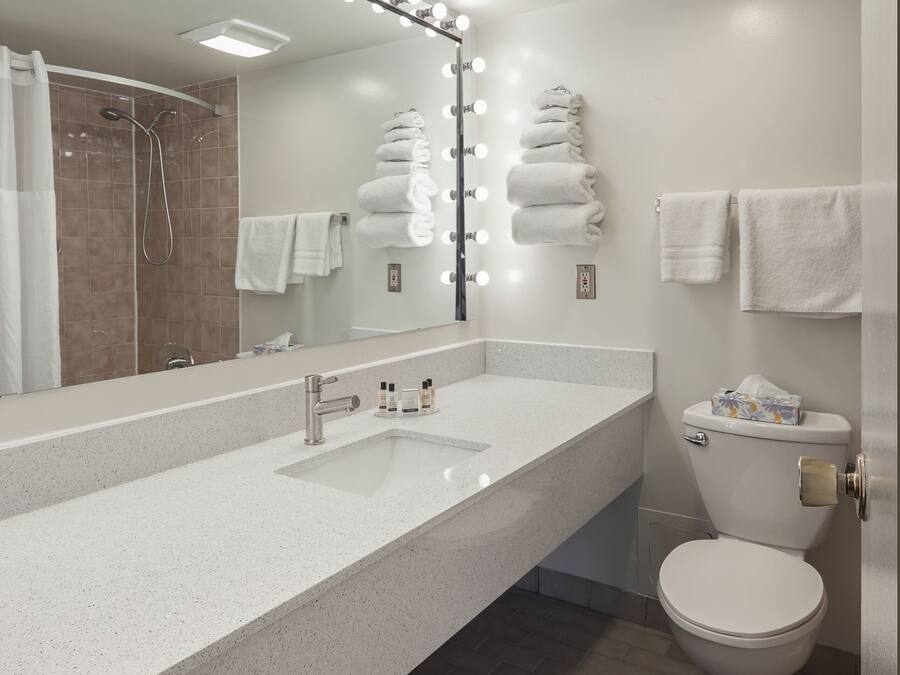 A modern bathroom with a large mirror, vanity, and a toilet.
