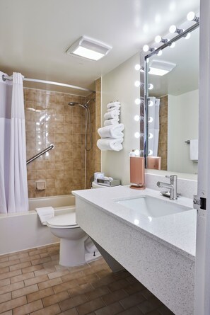 Un baño moderno con ducha, inodoro y lavamanos, equipado con un espejo de tocador e iluminación.