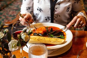 A dining table with a plate of food, a glass of red wine, and a glass of water.