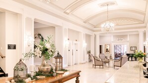 Un vestíbulo amplio con una recepción de mármol, elegantes candelabros y cómodas zonas de estar.
