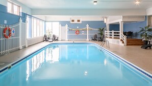 Piscina interior con agua cristalina azul, zona de piscina blanca y valla blanca con un flotador salvavidas.