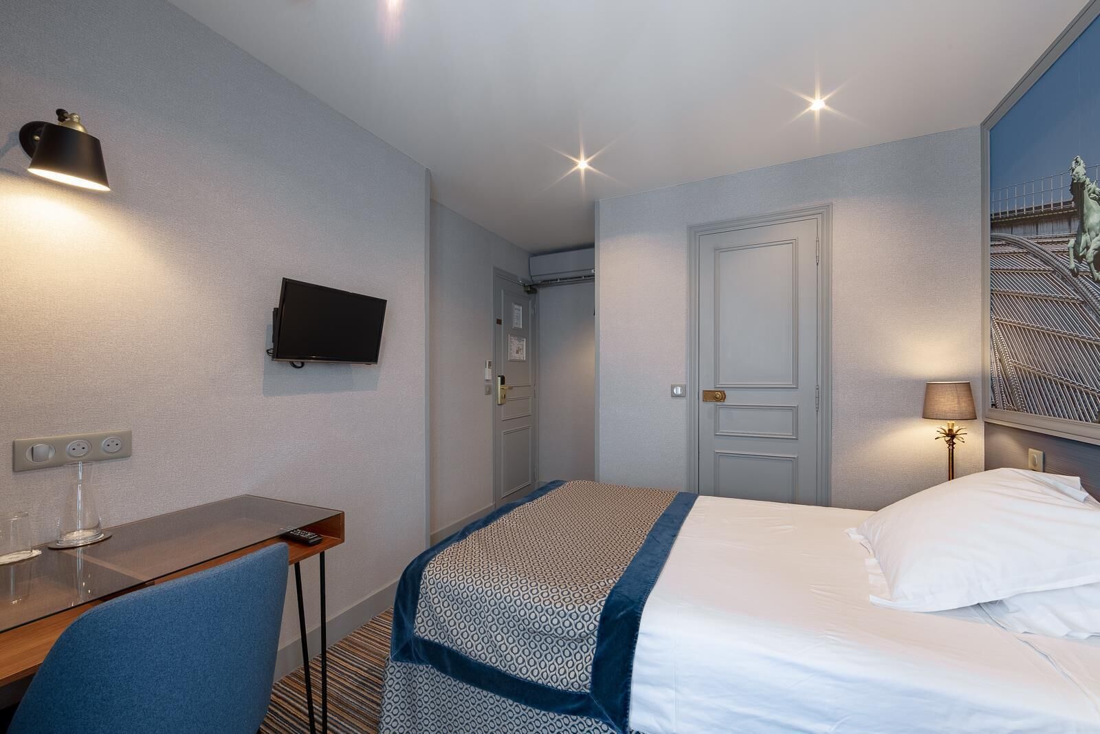 A hotel room with a bed, a desk, a TV, and a window with a view of a bridge.
