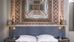 Un letto con lenzuola bianche, una testiera blu e due comodini con lampade.