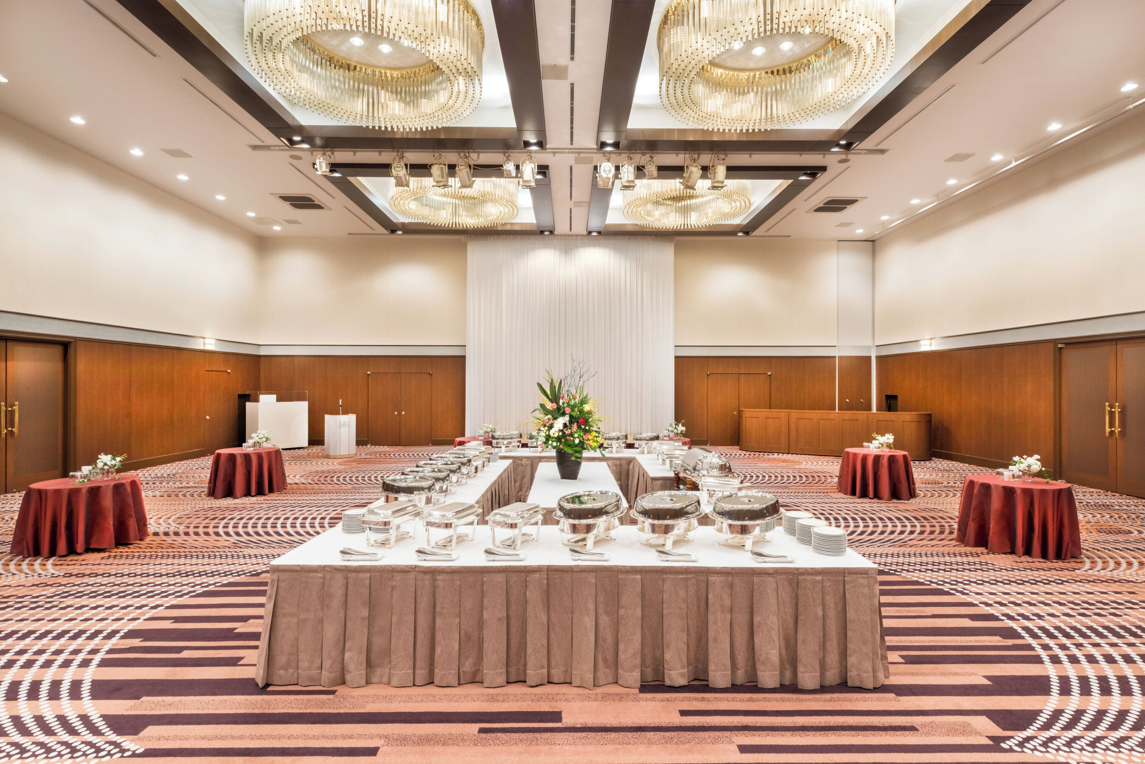 Un amplio salón de banquetes con una larga mesa dispuesta para un evento formal, rodeado de paneles de madera y grandes candelabros.