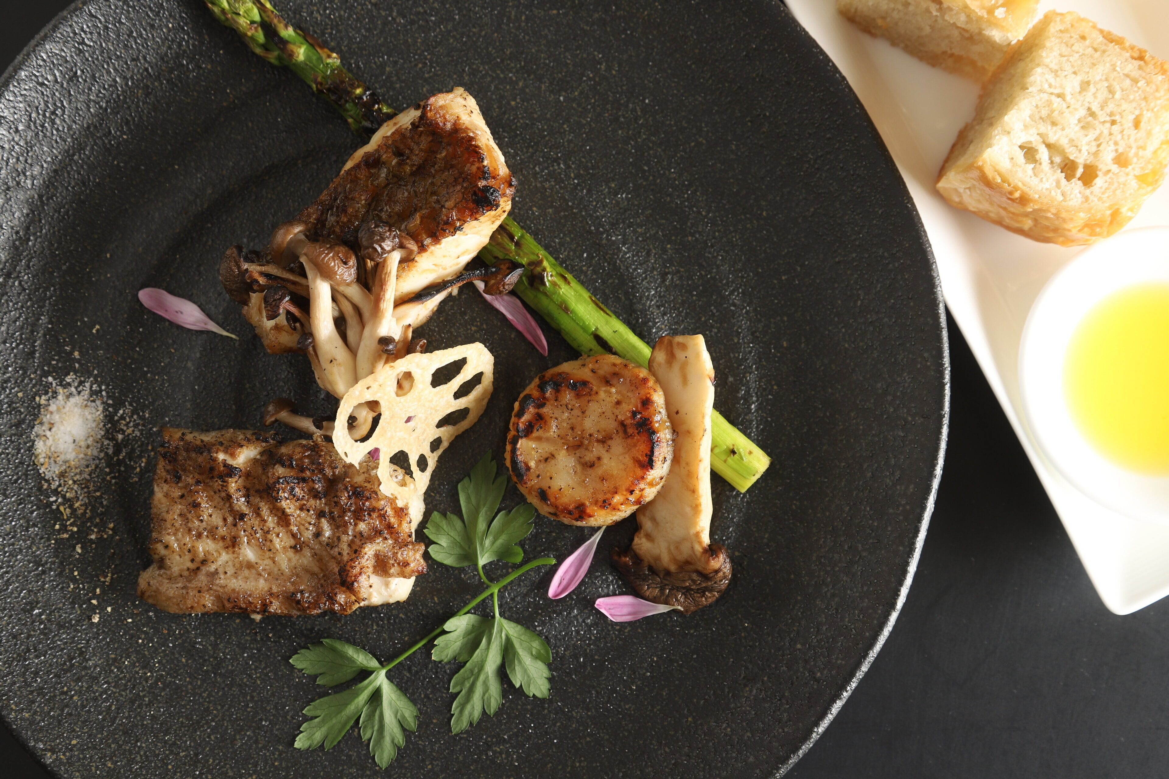 A plate with grilled meat, mushrooms, asparagus, and a garnish of parsley.